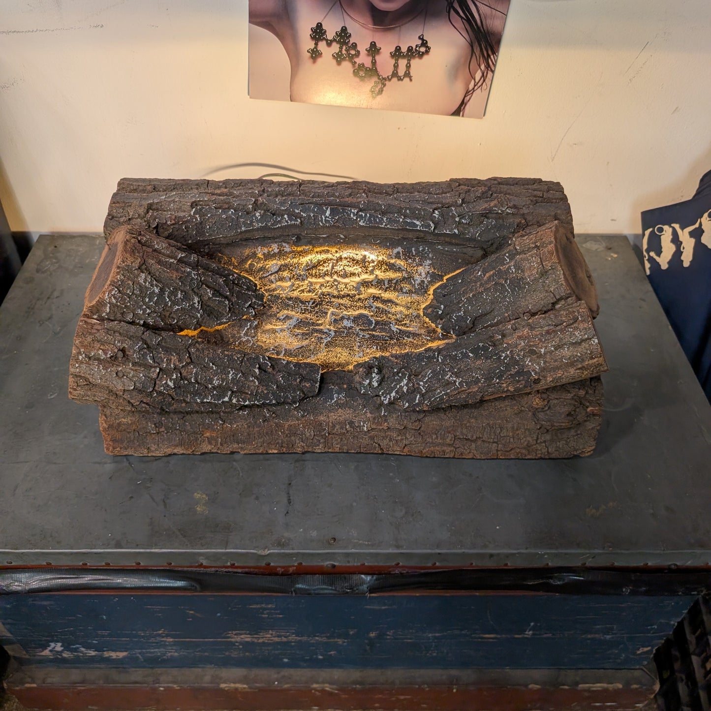 A rustic, bark-textured rectangular planter or tray with a glowing yellow-orange crack-like pattern in the center, displayed on a dark table in an indoor setting.